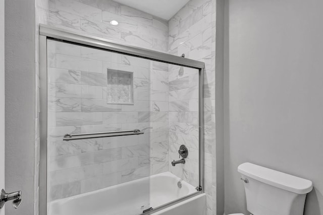 bathroom featuring toilet and combined bath / shower with glass door