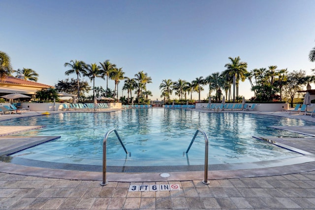 pool at dusk featuring a patio area