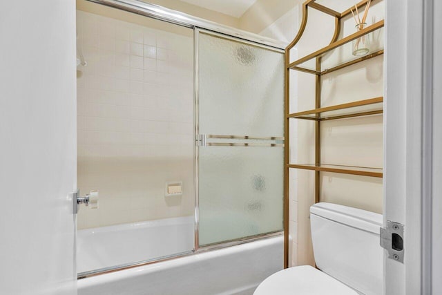 bathroom featuring toilet and bath / shower combo with glass door