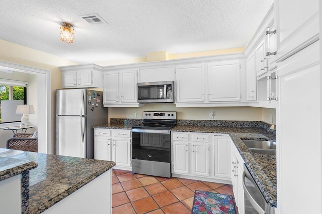 kitchen with visible vents, a textured ceiling, white cabinetry, a sink, and appliances with stainless steel finishes