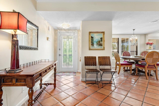 interior space with a textured ceiling, an inviting chandelier, plenty of natural light, and visible vents