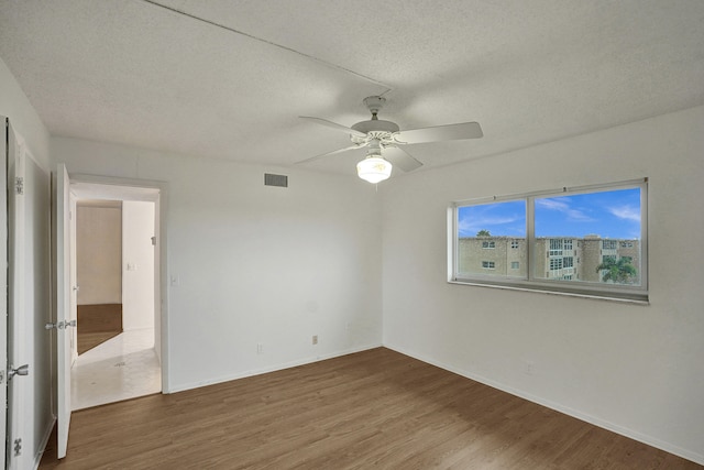 spare room with a textured ceiling, hardwood / wood-style flooring, and ceiling fan