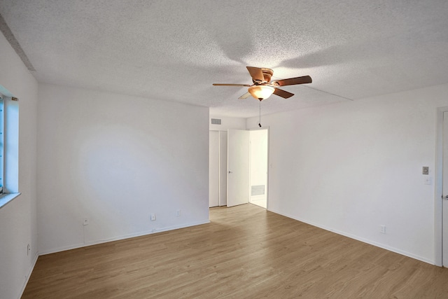 unfurnished room with a textured ceiling, light wood-type flooring, and ceiling fan