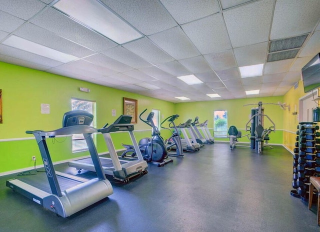 exercise room featuring a paneled ceiling and plenty of natural light