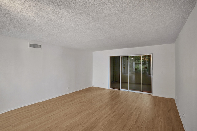 unfurnished room with a textured ceiling and light hardwood / wood-style flooring