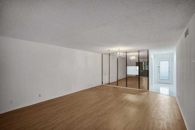 unfurnished bedroom featuring a closet, a chandelier, hardwood / wood-style flooring, and a textured ceiling