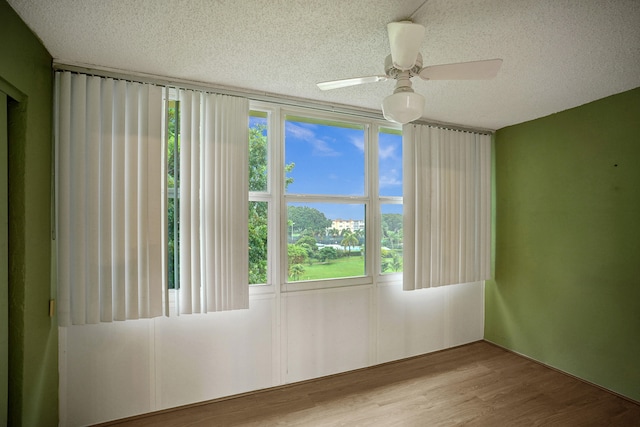 unfurnished room featuring light hardwood / wood-style floors, a textured ceiling, plenty of natural light, and ceiling fan