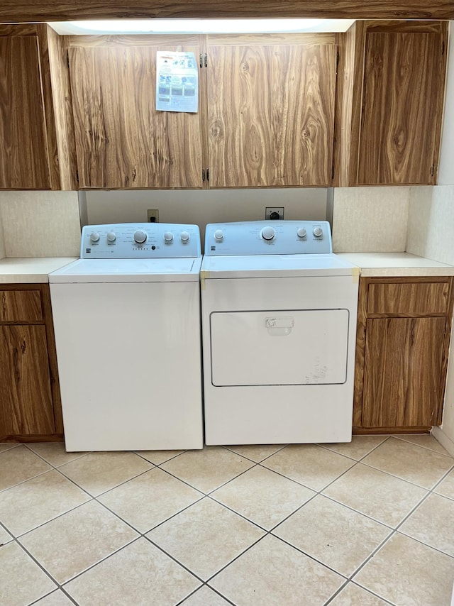 laundry room with cabinets, light tile patterned floors, and washing machine and clothes dryer