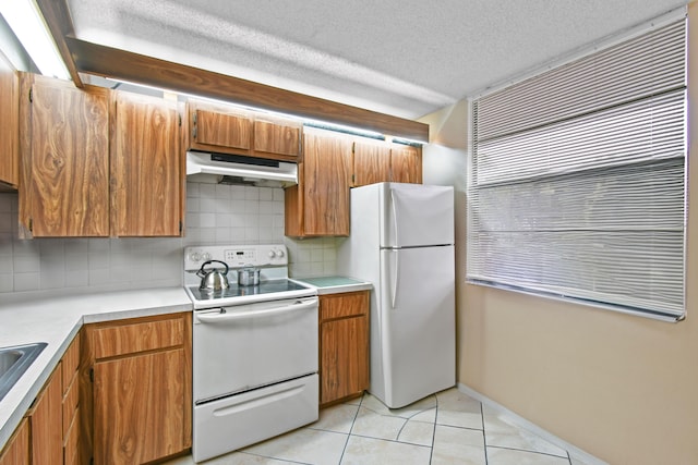 kitchen featuring white appliances, backsplash, sink, light tile patterned floors, and a textured ceiling