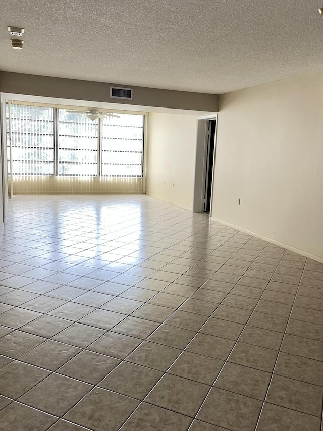 tiled empty room featuring a textured ceiling