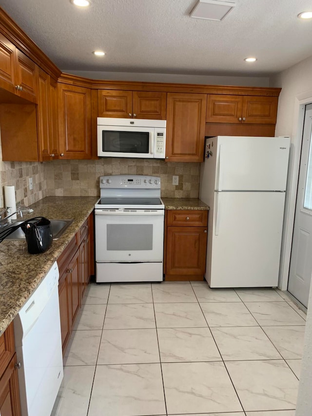 kitchen with sink, dark stone counters, a textured ceiling, white appliances, and decorative backsplash