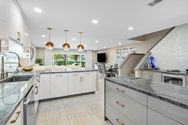 kitchen with pendant lighting, white cabinets, dark stone counters, decorative backsplash, and sink