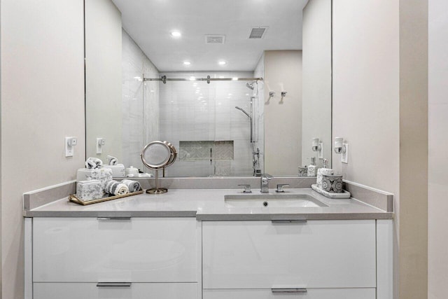 bathroom with a shower with shower door and vanity