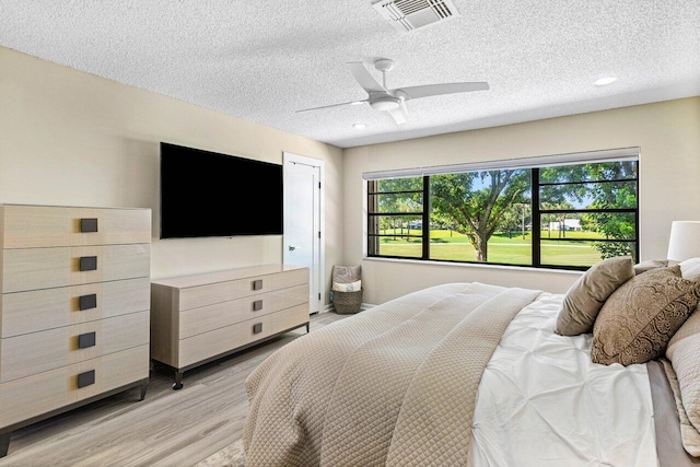 bedroom with ceiling fan, light wood-type flooring, and a textured ceiling