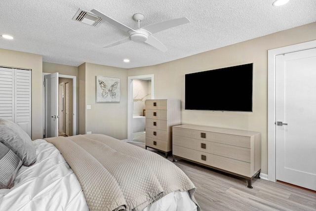 bedroom with a textured ceiling, ceiling fan, light hardwood / wood-style flooring, and multiple closets