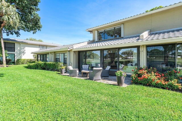 back of property featuring a patio area, a yard, and an outdoor hangout area