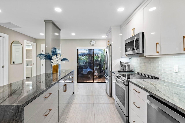 kitchen featuring white cabinets, stainless steel appliances, dark stone counters, and tasteful backsplash