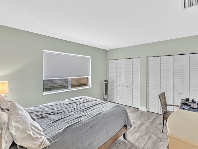 bedroom featuring light wood-type flooring and two closets