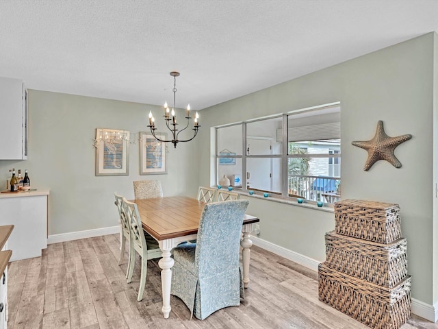 dining area featuring a textured ceiling, light wood-type flooring, and a chandelier