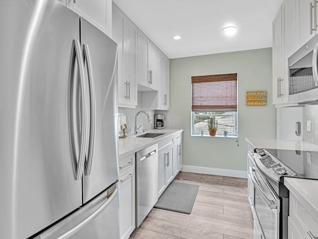 kitchen with light wood-type flooring, sink, stainless steel appliances, and white cabinets