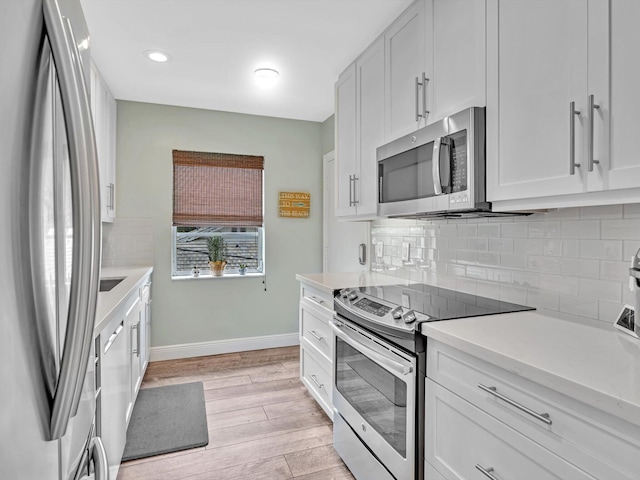 kitchen with light hardwood / wood-style flooring, stainless steel appliances, decorative backsplash, and white cabinetry