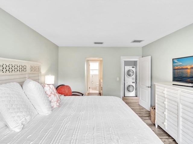 bedroom featuring stacked washer / drying machine and dark hardwood / wood-style floors