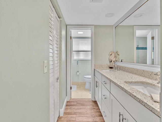 bathroom with vanity, a shower, hardwood / wood-style floors, and toilet