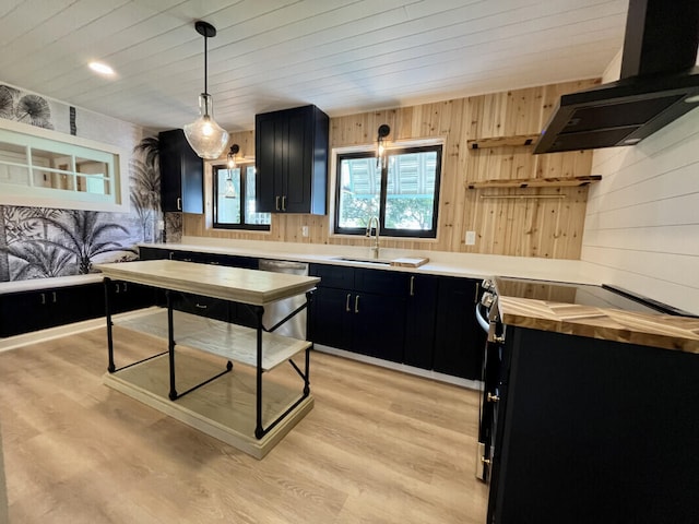 kitchen featuring wood walls, pendant lighting, exhaust hood, light wood-type flooring, and sink