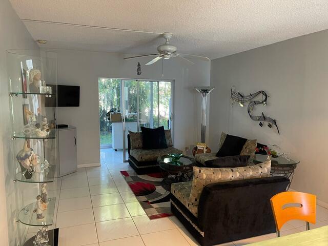 living room featuring a textured ceiling, ceiling fan, and tile patterned flooring