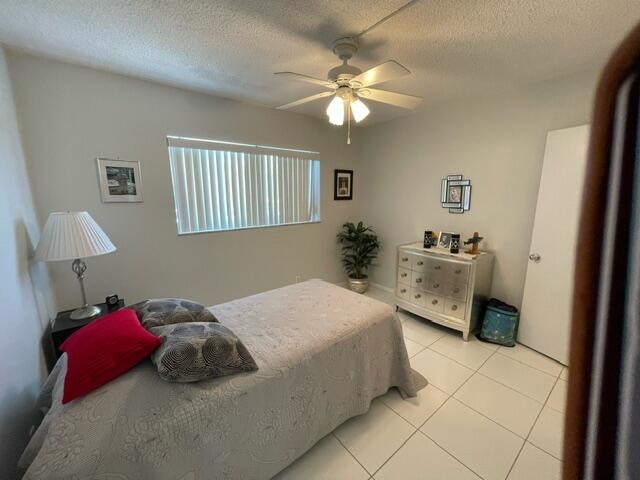 bedroom featuring ceiling fan, light tile patterned flooring, and a textured ceiling