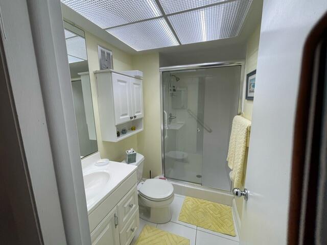 bathroom with toilet, vanity, a stall shower, and tile patterned flooring