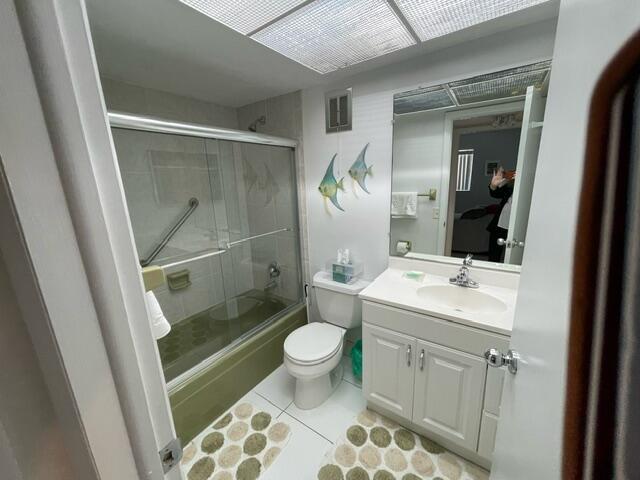 full bathroom featuring vanity, toilet, tile patterned floors, visible vents, and enclosed tub / shower combo