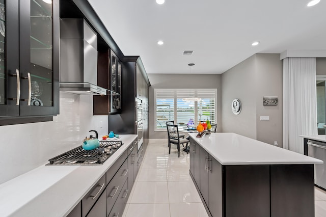 kitchen with stainless steel appliances, wall chimney range hood, and a kitchen island