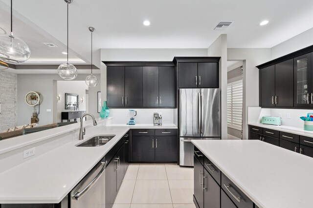 kitchen with sink, a center island, decorative light fixtures, light tile patterned floors, and appliances with stainless steel finishes