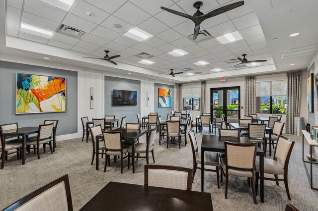 dining space featuring light carpet, a drop ceiling, and a raised ceiling