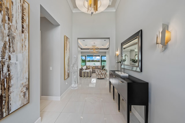 hallway featuring ornamental molding, a notable chandelier, and a raised ceiling