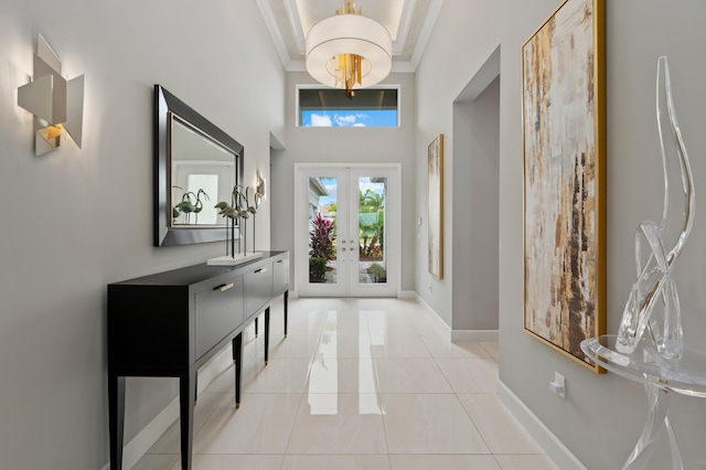 foyer entrance featuring french doors, crown molding, a towering ceiling, and light tile patterned floors