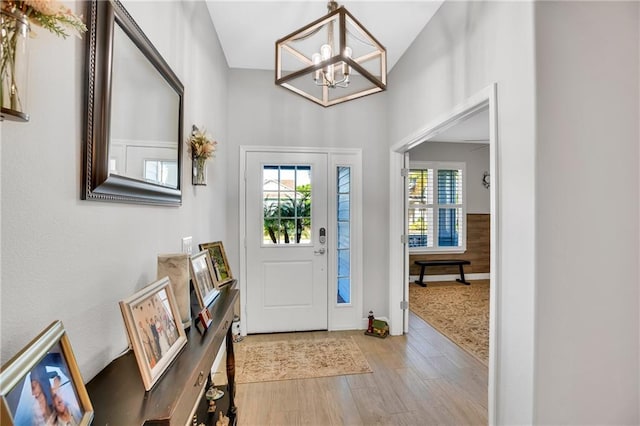 foyer featuring a notable chandelier, light wood-type flooring, and vaulted ceiling