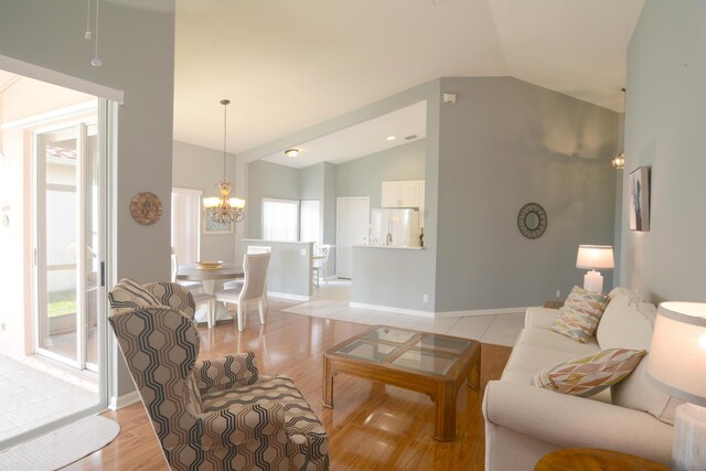 living room with light wood-type flooring, an inviting chandelier, and high vaulted ceiling