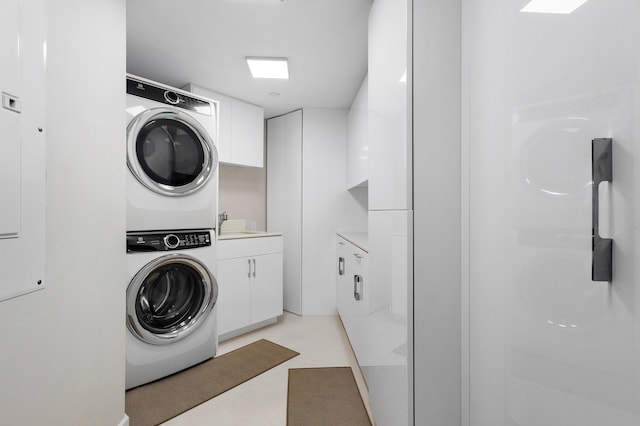 washroom featuring cabinets and stacked washer and clothes dryer