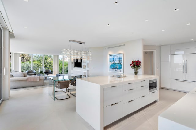 kitchen featuring white cabinets, decorative light fixtures, built in appliances, and a center island