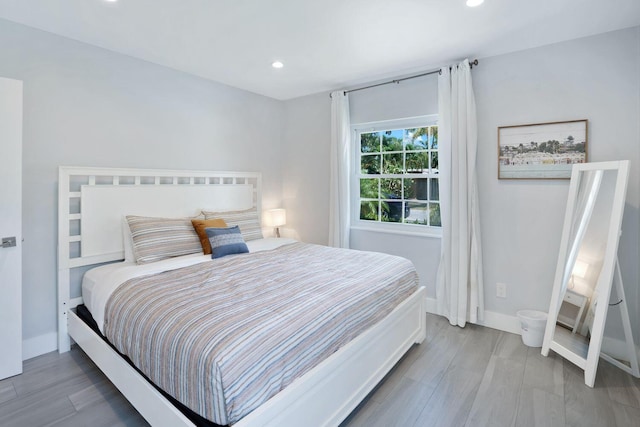 bedroom featuring wood finished floors, baseboards, and recessed lighting