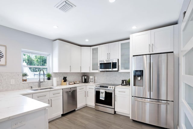 kitchen featuring tasteful backsplash, white cabinets, visible vents, appliances with stainless steel finishes, and a sink