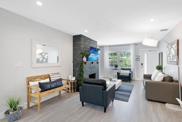 living room with a large fireplace, visible vents, light wood finished floors, and recessed lighting