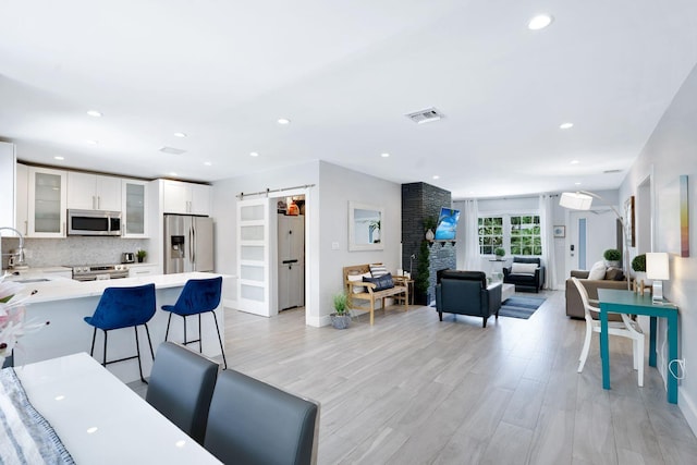 interior space with a large fireplace, visible vents, recessed lighting, and light wood-style floors
