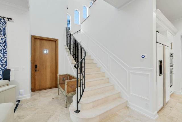 entryway featuring a towering ceiling and ornamental molding