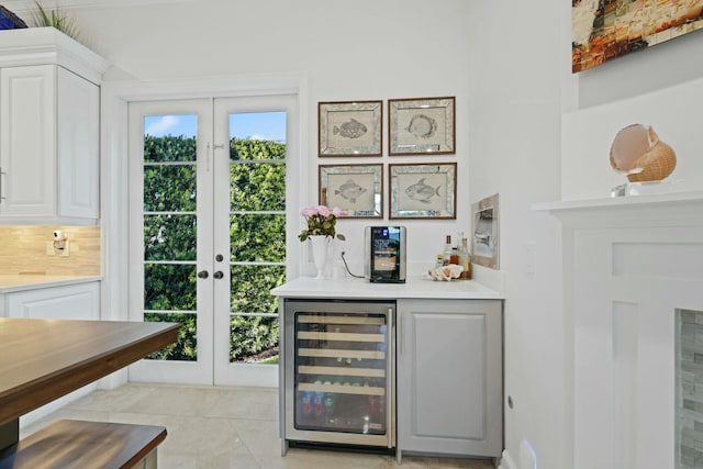 bar featuring white cabinets, french doors, light tile patterned floors, and beverage cooler