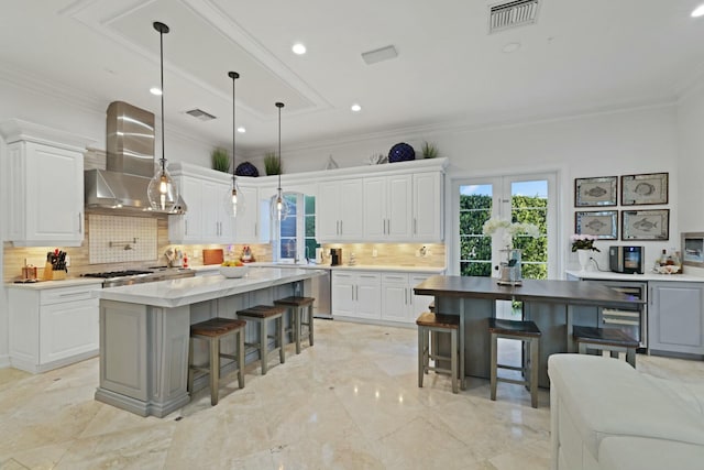 kitchen featuring white cabinets, a center island, and wall chimney exhaust hood