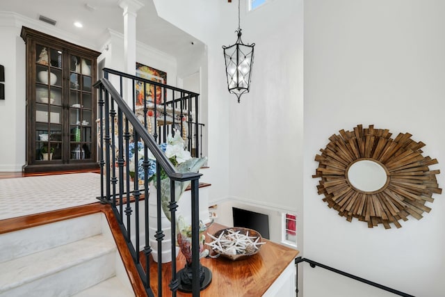 stairs with wood-type flooring, ornamental molding, and a notable chandelier