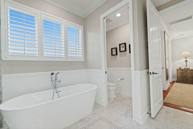 bathroom with toilet, crown molding, and a bathing tub